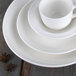 A stack of Libbey Royal Rideau white porcelain grapefruit bowls with a white background.