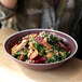 A Libbey Englewood matte mulberry salad bowl filled with a kale salad with beets and carrots.