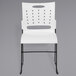 A white plastic Flash Furniture stack chair with air-vent holes.
