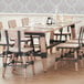 A Lancaster Table & Seating wooden dining table with chairs and glasses on it.