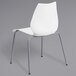 A white Flash Furniture stack chair with metal legs.