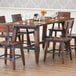 A Lancaster Table & Seating wooden trestle table base for a dining table with chairs.