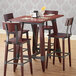 A Lancaster Table & Seating wooden trestle table base with chairs and a bar stool on a table in a restaurant dining area.