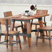A Lancaster Table & Seating solid wood dining table with chairs and glasses on it.