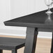 A Lancaster Table & Seating live edge trestle table with a wine glass on it.
