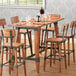 A Lancaster Table & Seating wood trestle table with chairs and wine glasses.