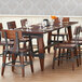 A Lancaster Table & Seating solid wood dining table with wine glasses on it.
