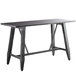 A black Lancaster Table & Seating solid wood live edge bar height trestle table with legs.