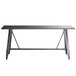 A Lancaster Table & Seating solid wood live edge bar height trestle table in antique slate gray with legs.