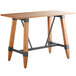 A Lancaster Table & Seating bar height wooden table with metal legs.