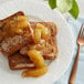 A plate of french toast topped with Lucky Leaf apple filling next to a fork.