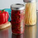 A Ball wide mouth glass canning jar filled with red and yellow peppers.
