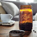 A Ball Quart Elite amber glass canning jar filled with coffee beans on a table.