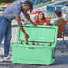A man wearing a hat putting a can into a CaterGator Seafoam outdoor cooler while a woman and child smile at the camera.