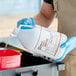 A person in blue gloves pouring Noble Chemical Sani-512 sanitizer from a white jug into a container.