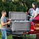 A man and woman loading a CaterGator outdoor cooler into a truck.