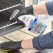 A person in gloves spraying a grill with SC Johnson fantastik Max Oven and Grill Cleaner.