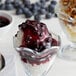 A glass cup of blueberry dessert topping with walnuts and blueberries.