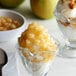 A glass cup of I. Rice Spiced Apple Dessert Topping with apples and caramel sauce.
