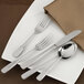 A white plate with a Walco stainless steel iced tea spoon on a napkin.