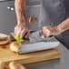 A man using a Prince Castle bagel slicer to cut bagels on a cutting board.