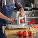 A man using a Prince Castle tomato slicer to cut a tomato.