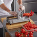 A person using a Prince Castle tomato slicer to slice tomatoes on a cutting board.