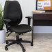 A Boss black high back office chair next to a desk with a plant on it.