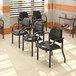 A group of black Boss antimicrobial guest chairs with armrests in a room.