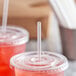 A close-up of a plastic cup with a clear wrapped straw in it.