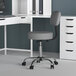 A gray Boss office stool with a backrest at a white desk with a computer.