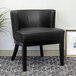 A black Boss Ava accent chair in a lounge area with a plant in front of it.