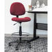A Boss burgundy drafting stool with footring on a metal base.