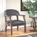 A Boss Slate Gray Linen Modern Captain's Chair with wooden legs next to a table with a plant on it.