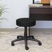 A Boss black mesh DOT stool with wheels sitting in front of a desk.
