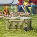 A CaterGator camouflage cooler on grass with people sitting around it.
