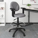 A gray Boss drafting stool with a metal footring and black arms.