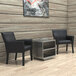 A black Boss executive chair in a lounge area with a wood wall and a grey table with shelves.