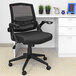 A black Boss office chair with wheels in front of a desk.