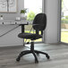 A black Boss Perfect Posture office chair with adjustable arms at a desk in a room with a plant.