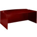 A mahogany laminate bow front desk shell on a table with a white mouse pad.