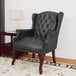 A Boss black leather wingback guest chair with wooden legs.