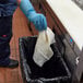 A person in blue gloves using a white towel to clean a stainless steel surface.
