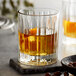 A Libbey Flashback double old fashioned glass filled with a drink and ice on a stone surface.