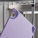 A purple San Jamar allergen-free cutting board hanging from a hook.