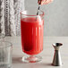 A person stirring a red drink in a Libbey Flashback stirring glass.