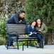 A man and a woman sitting on a Lifetime gray glider bench with a girl reading a book.