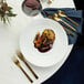 A white plate of food with a Oneida Chef's Table Gold stainless steel dessert fork on a table.