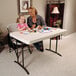 A woman and a girl painting at a white Lifetime plastic folding table.