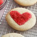Heart-shaped cookies with red sanding sugar on a cooling rack.